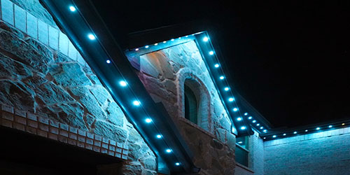 Oelo permanent lights on a stone house at night